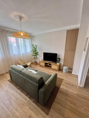 Un salon moderne avec un canapé, un téléviseur et un plancher en bois.