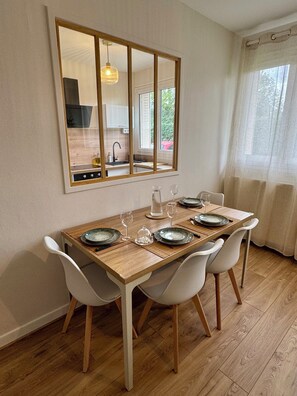 Ein Essbereich mit einem Holztisch, gedeckt für vier Personen, weißen Stühlen und einem großen Spiegel darüber.