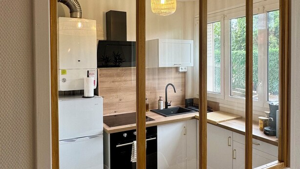 A modern kitchen with a large window, a built-in oven, and a hanging light fixture. - L'Escale Nippone – Wi-Fi – Free Parking (Vichy)
