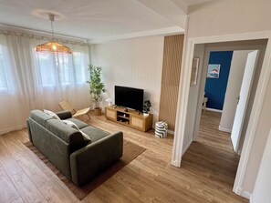 A modern living room with a sofa, TV, and a potted plant. - L'Escale Nippone – Wi-Fi – Free Parking (Vichy)
