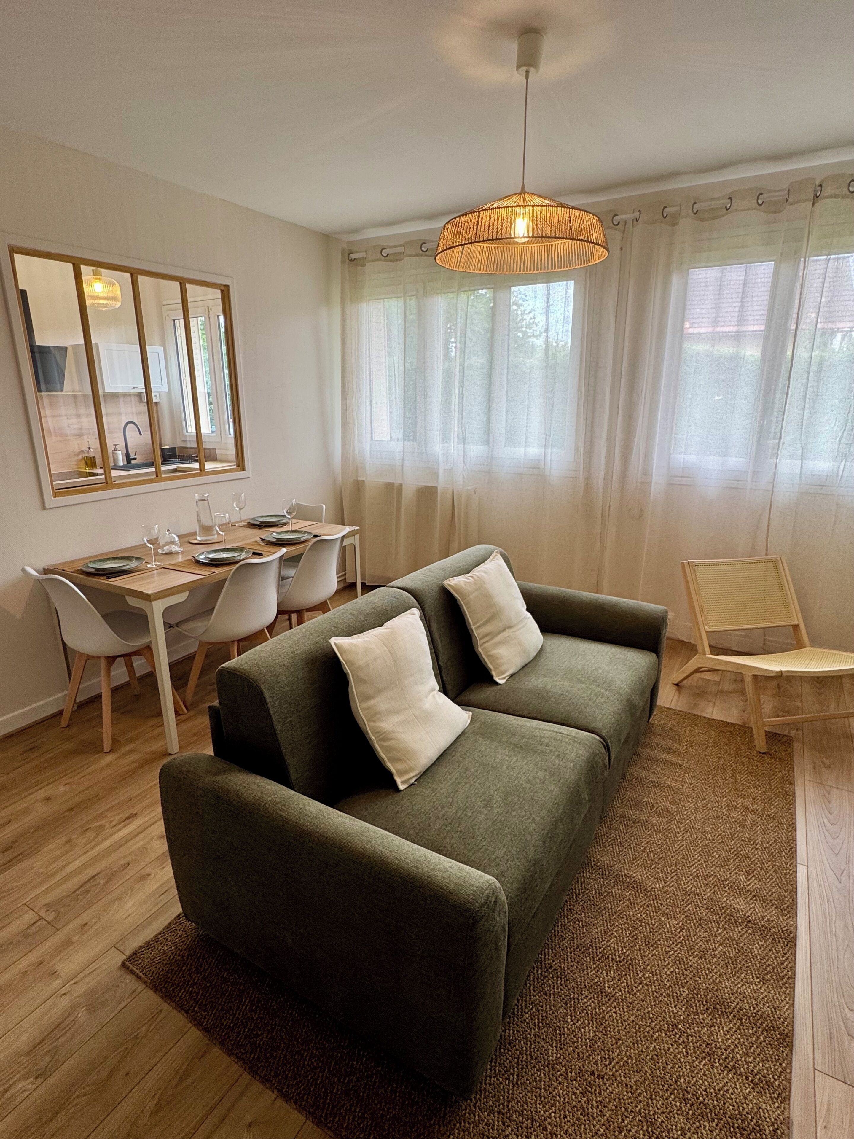 Un salon moderne comprenant un canapé, des fauteuils, une table à manger et un luminaire suspendu.