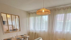 A modern living room with a sofa, chairs, a dining table, and a hanging light fixture. - L'Escale Nippone – Wi-Fi – Free Parking (Vichy)