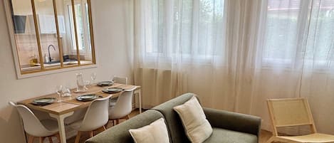 Un salon moderne comprenant un canapé, des fauteuils, une table à manger et un luminaire suspendu.
