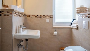 Un bagno con lavandino, WC e finestra dotata di persiane.
