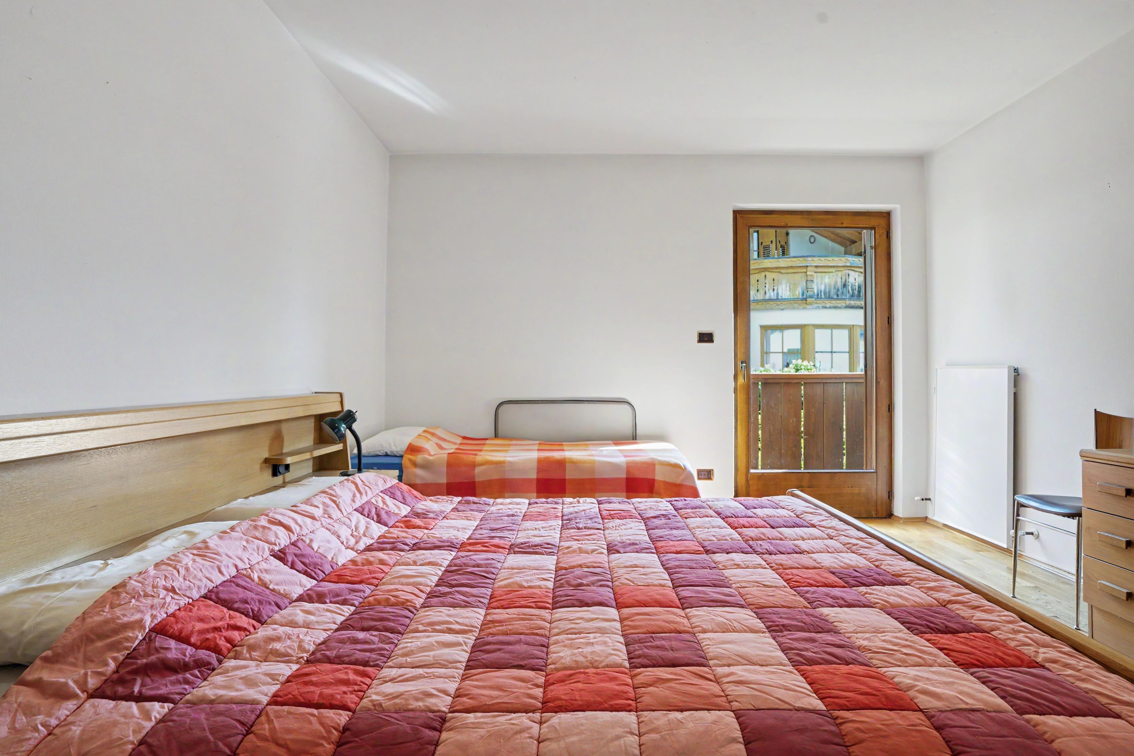 Ein Schlafzimmer mit einem großen Bett, einem Holzkopfstück, einem Nachttisch mit Lampe und einer Holzkommode.