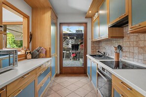 A kitchen with wooden cabinets, a built-in oven, and a view into the backyard.