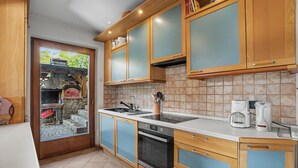 Una cocina con armarios de madera, horno empotrado, cafetera y vistas al exterior.