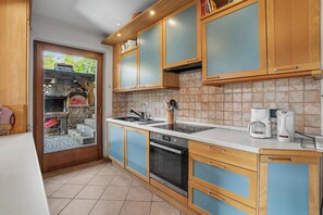 A kitchen with wooden cabinets, a built-in oven, a coffee maker, and a view of the outside. - Villa '' with Mountain View, Private Terrace and Wi-Fi (Altavalle)