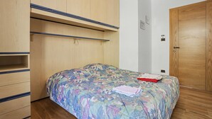 Un dormitorio con cama, armario de madera y una puerta.