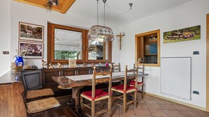 Un comedor con una mesa y sillas de madera, una araña y techo de madera.