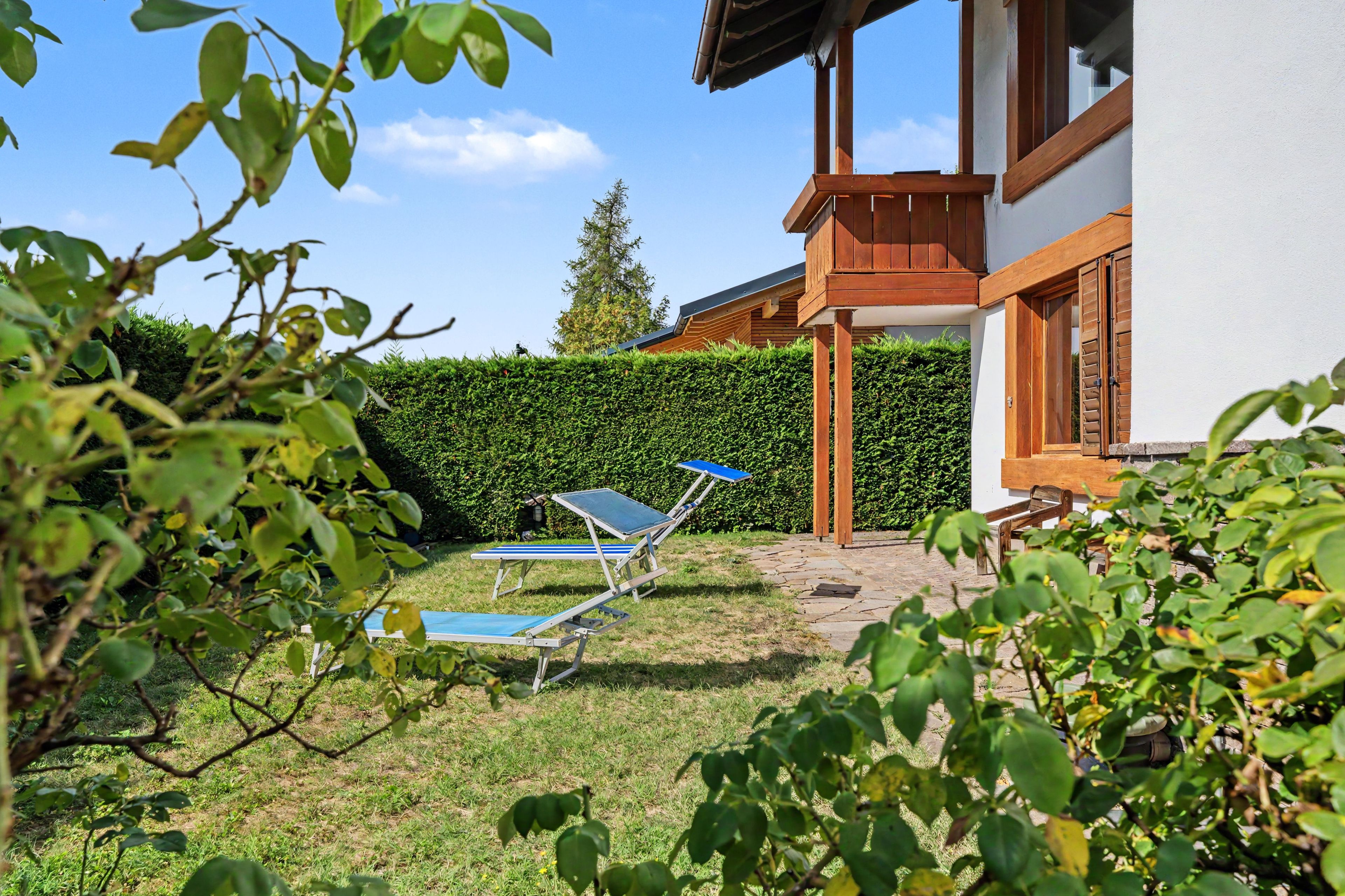 Ein Wohnhaus mit gepflegtem Rasen, einer Holzterrasse und einem solarbetriebenen Elektroroller.