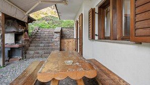 Un patio al aire libre con una mesa de madera, escalones de piedra y una pared de ladrillo.