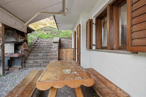 An outdoor patio with a wooden table, stone steps, and a brick wall. - Villa '' with Mountain View, Private Terrace and Wi-Fi (Altavalle)