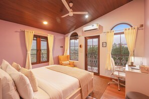 A bedroom with a bed, a desk, and a chair, a ceiling fan, and a window with curtains.