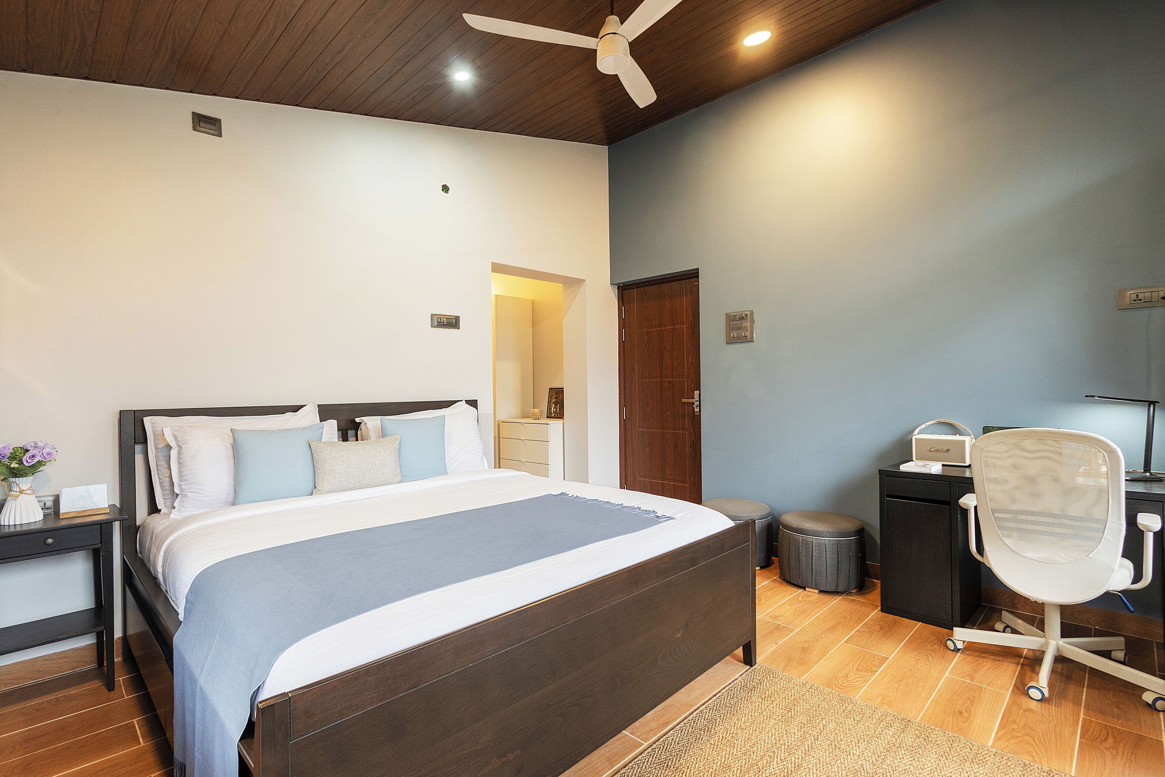 A bedroom with a bed, a desk, a chair, and a ceiling fan.