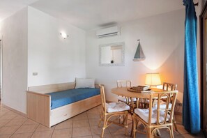 A room with a bed, a table with chairs, a lamp, and a mirror on the wall. - Casa Franca – terrace with a view of the bay, 200 meters from the sea (Golfo Aranci)