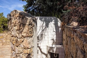 A stone-walled outdoor toilet with a tiled wall and a sink. - Casa Franca – terrace with a view of the bay, 200 meters from the sea (Golfo Aranci)