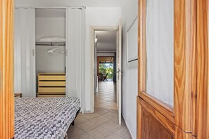 Un couloir étroit avec un lit, une armoire et une porte donnant sur un coin repas.