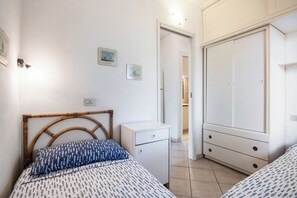 A bedroom with two beds, a wardrobe, a small desk, and a door leading to another room. - Casa Franca – terrace with a view of the bay, 200 meters from the sea (Golfo Aranci)