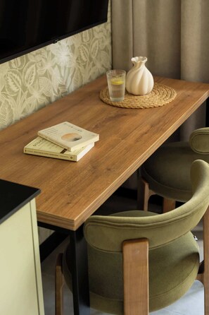 A wooden table with a book, a glass of water, and a vase. There are two chairs with cushions. - Pułaskiego 7A | Perfect for Couples | AC (Kraków)
