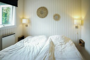 Una habitació amb un llit, dues làmpades murals i una finestra amb persianes.