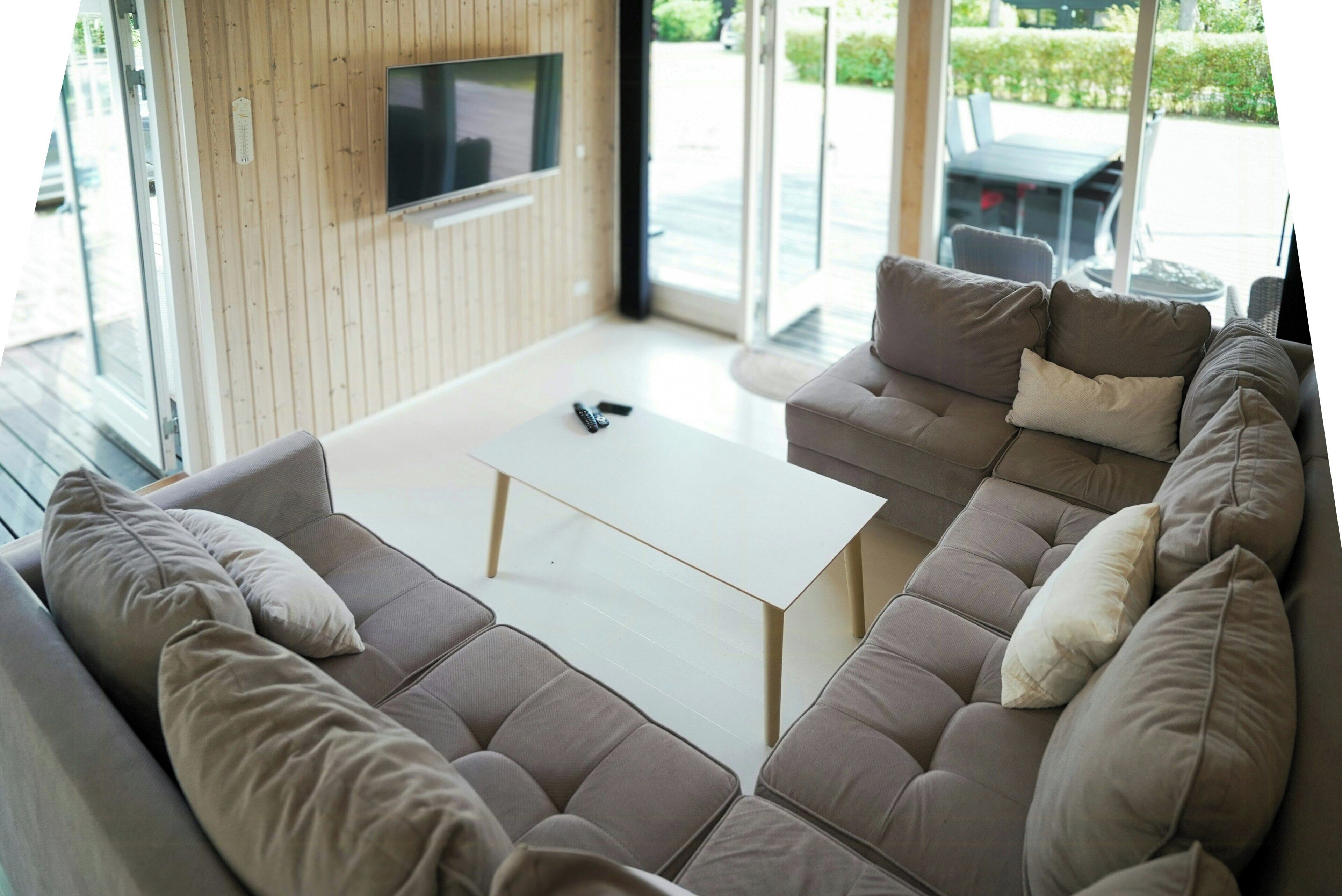 A modern living room with a sectional sofa, a flat-screen TV mounted on the wall, and a small coffee table.