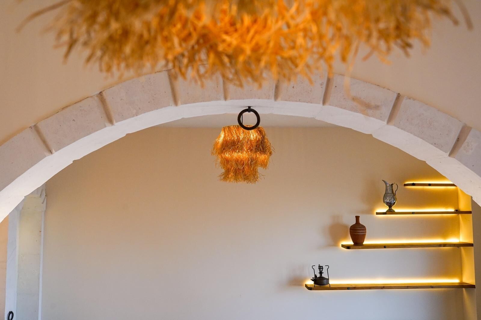 A room with a white arched ceiling, a hanging light fixture, and shelves with decorative items.