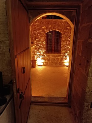 Un arco de entrada a un cuarto con pared de piedra y una ventana con rejas.