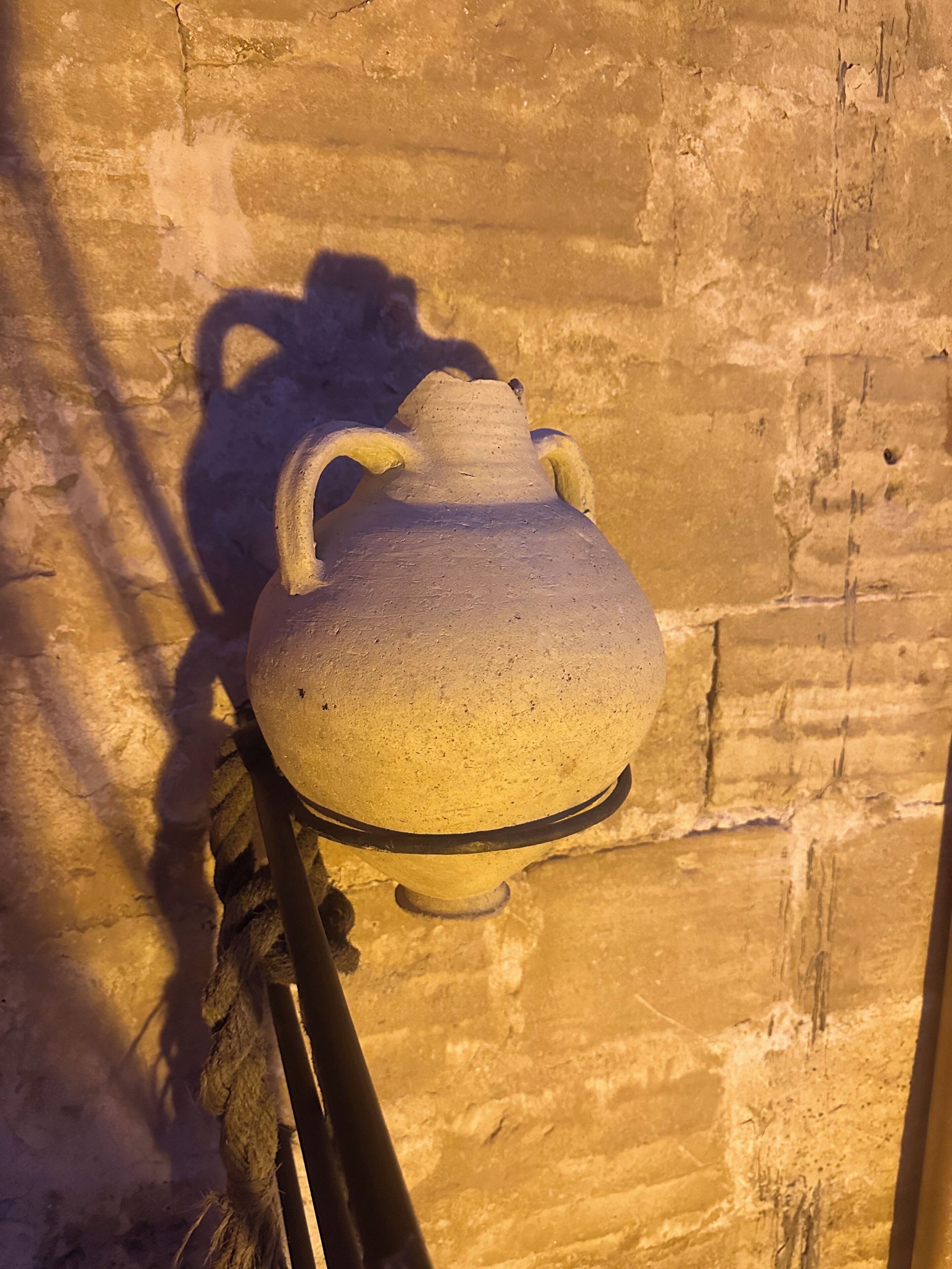 Una jarra de cerámica montada en la pared, proyectando una sombra sobre la superficie.
