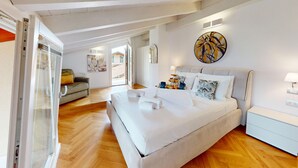 A spacious bedroom with a large bed, a sofa, and a glass door leading to a balcony. - Sirmio Dream View Suite by Bookinggardalake (Sirmione)