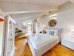 A spacious bedroom with a large bed, a sofa, and a glass door leading to a balcony. - Sirmio Dream View Suite by Bookinggardalake (Sirmione)