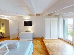 Ein Hotelzimmer mit Bett, Nachttisch, Fernseher und Blick durch die Tür.