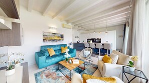 Ein modernes Wohnzimmer mit einem blauen Sofa, einem Couchtisch und einem Essbereich mit Stühlen.