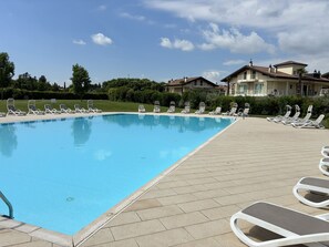 A swimming pool with lounge chairs and a paved deck. - Sirmio Dream View Suite by Bookinggardalake (Sirmione)