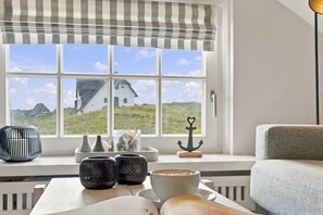 Une pièce dotée d’une grande fenêtre, offrant une vue sur une maison, et comprenant une table agrémentée d’objets décoratifs.