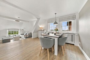 A modern interior with a dining area, kitchen, and living space. - Rundblick Building, Apartment 8 (Sylt)