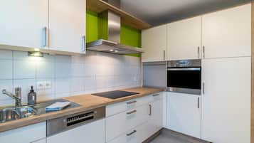 Eine moderne Küche mit weißen Schränken, einer Edelstahl-Dunstabzugshaube, einem Backofen und einem Geschirrspüler.