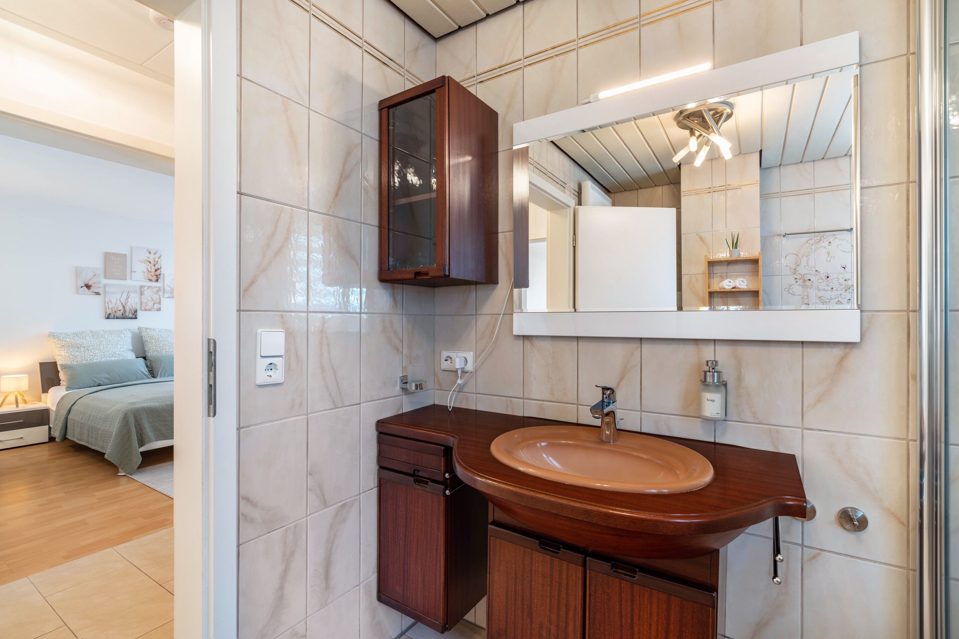 Ein modernes Badezimmer mit einem Holzkosmetikschrank, einem großen Spiegel und einem integriertem Waschbecken.