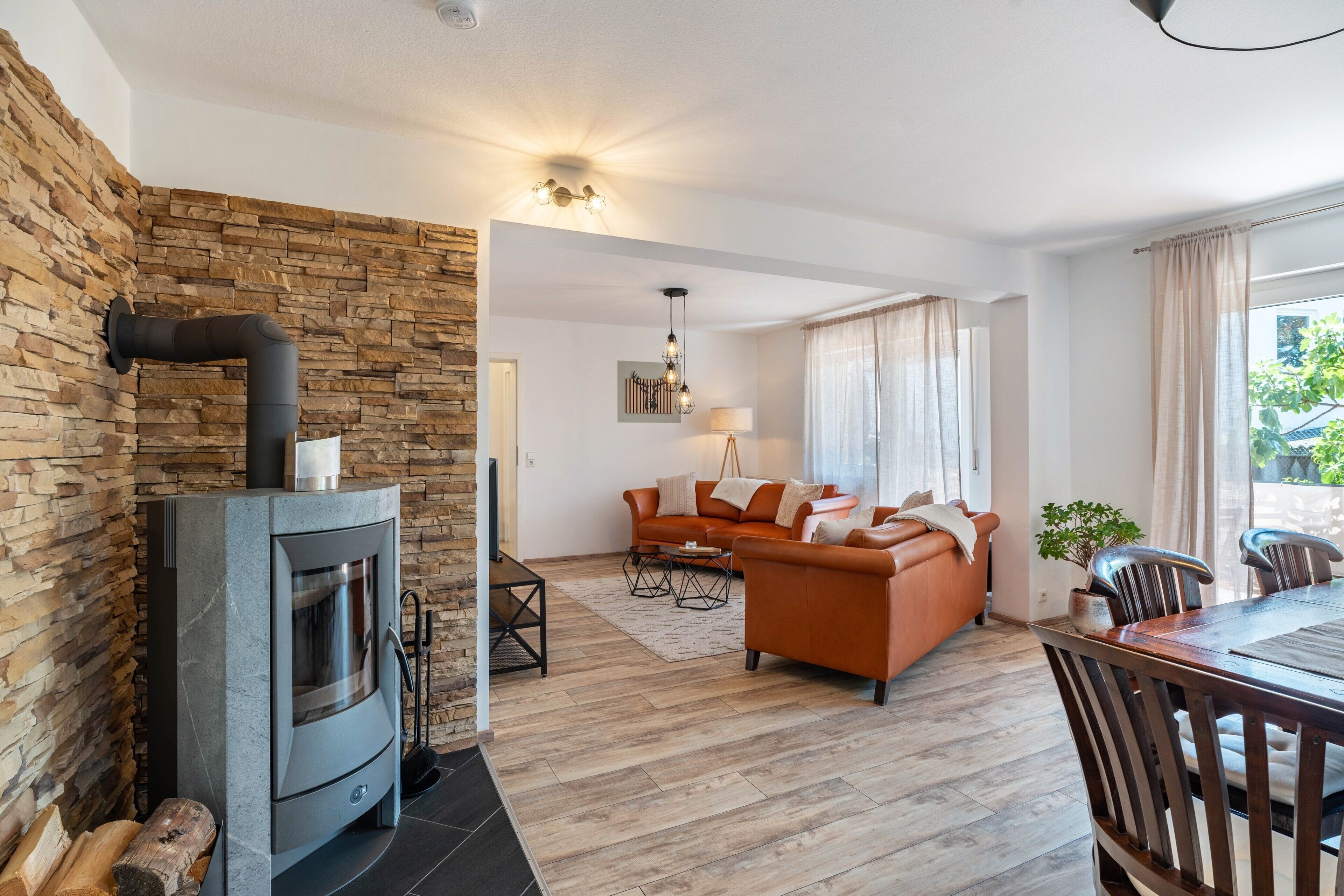 Una sala de estar moderna con pared de piedra, chimenea, sofá y comedor.