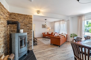 Una sala de estar moderna con pared de piedra, chimenea, sofá y comedor.