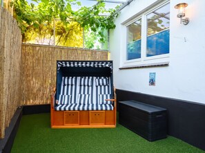 A small outdoor seating area with a striped bench and a wall-mounted light fixture. - Modern Ostdeich vacation rental in Büsum with a terrace for the whole family (Büsum)