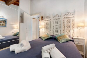 Habitación de hotel con una cama grande, dos mesitas de noche, un espejo y un cabecero decorativo.