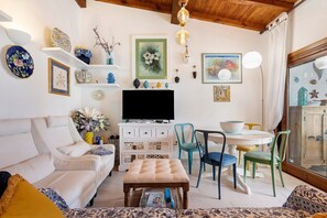 Una sala de estar con un sofá, una mesa de centro, un televisor y un comedor con sillas y una mesa.