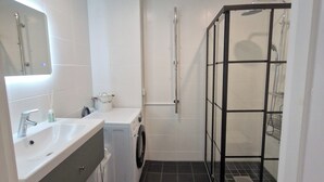 Ein modernes Badezimmer mit einem weißen Waschbecken, einem Spiegel und einer Duschkabine.