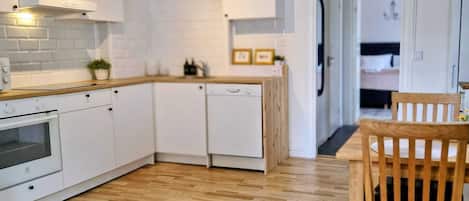 A modern kitchen with white cabinetry, a wooden countertop, and a built-in dishwasher.