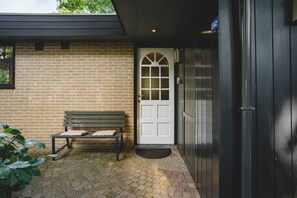 Un edificio in mattoni con una porta bianca, una panchina e un cancello nero.
