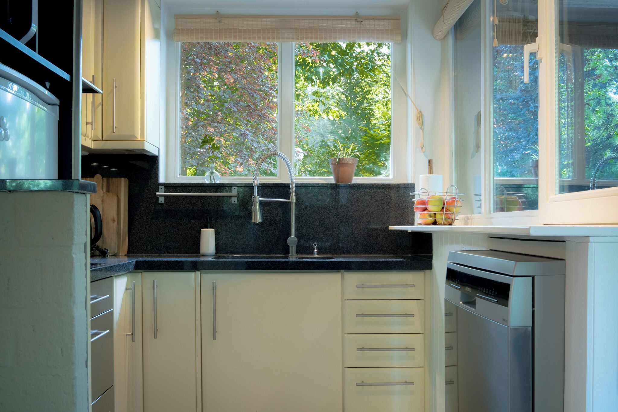 Una cocina con ventana, un lavamanos, armarios y lavavajillas.