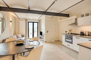A modern kitchen with a dining area, a large window, and a built-in oven.