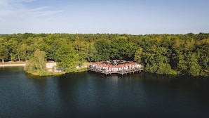 Une propriété située au bord d’un lac, avec une jetée qui s’avance dans l’eau, et entourée d’une forêt dense.