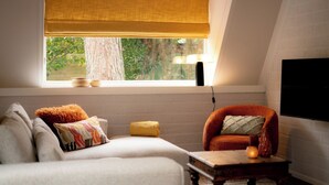 Een gezellige kamer met een bank, fauteuil en een tafel met lamp.